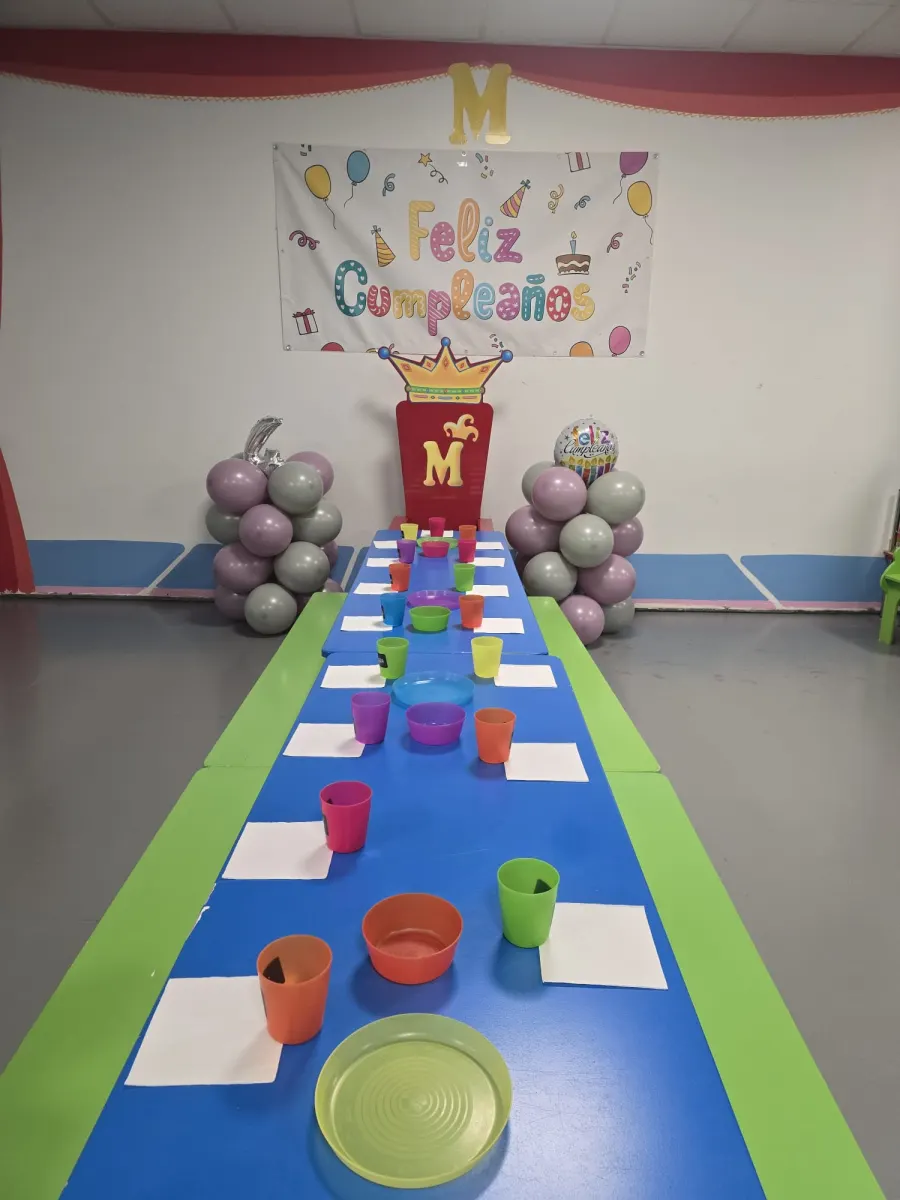 Mesa de cumpleaños montada en Ludoteca Menuts con vasos, cuencos y globos