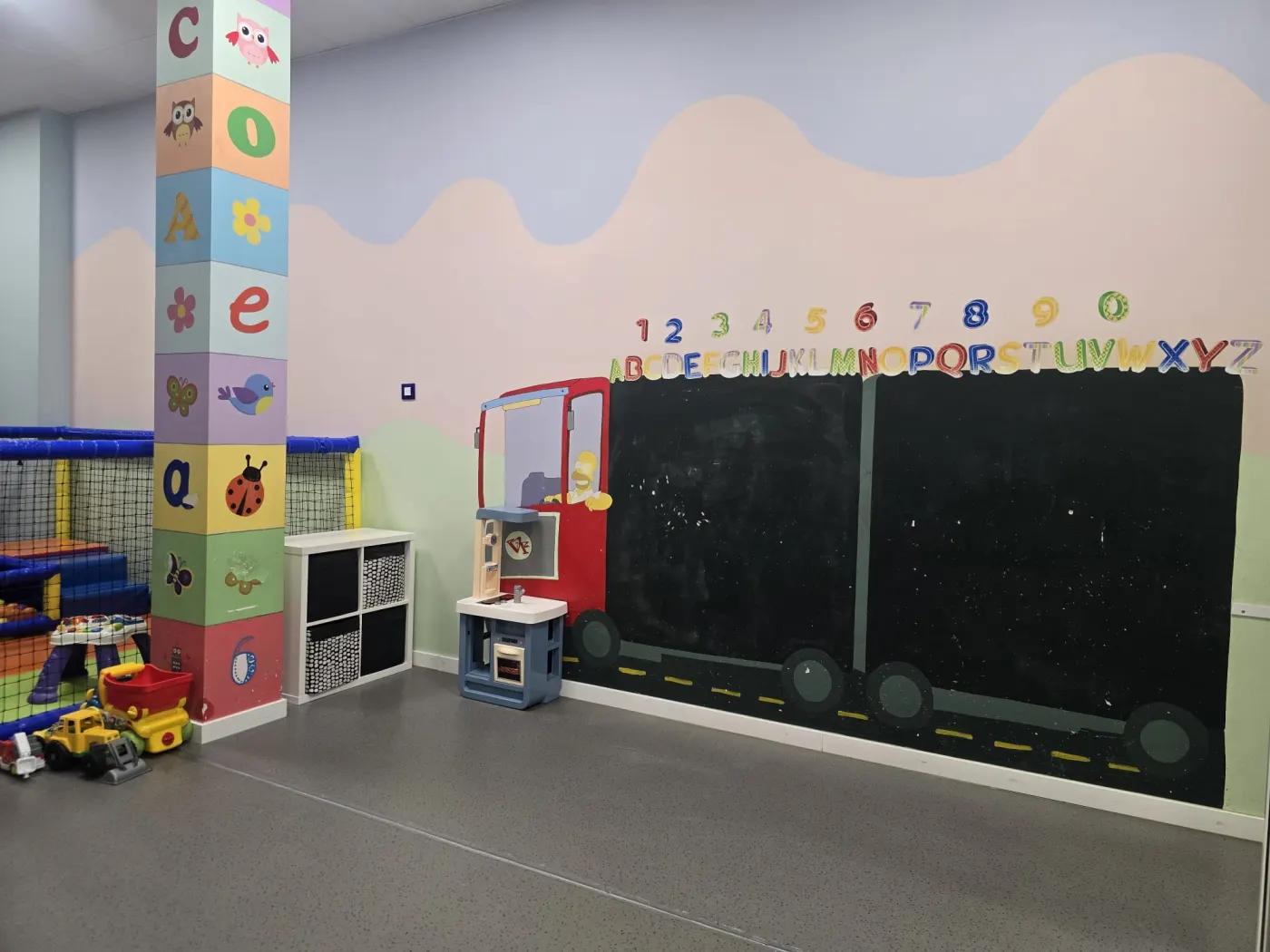 Zona de aprendizaje con pizarra en forma de camión, letras y números